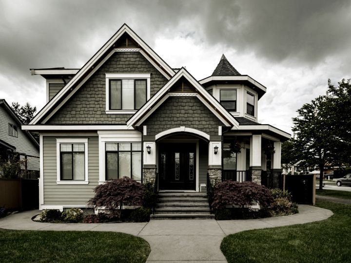 A symmetrical two-story house with a dark roof, stone and siding facade, and a covered front porch under an overcast sky becomes the serene setting for divorce mediation sessions held by Fairway Divorce